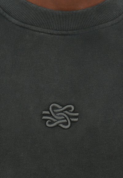 Mørkegrå sweatshirt med ribbet halsudskæring, prydet med et broderet logo i matchende grå på nederste venstre side. Glat stofstruktur.