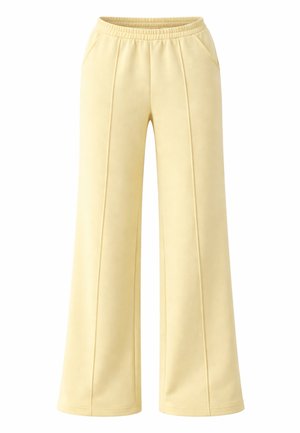 Pantalon large jaune clair avec taille élastique, détails de coutures au devant et poches latérales, conçu pour un usage décontracté.