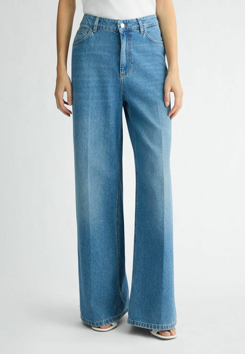 Lichtblauwe wijduitlopende jeans van denim, met een hoge taille, voorzakken, een ritssluiting en een licht vervaagde afwerking.