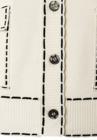 White knitted cardigan with black dashed lines along the edges, three visible buttons labeled "MORE," and two front pockets.