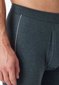 Grau-blau gestreifte Baumwollmischung-Boxershorts mit einem weichen Bund und weißen Seitenstichen. Nahaufnahme zeigt eine Hand, die auf der Stofftextur ruht.