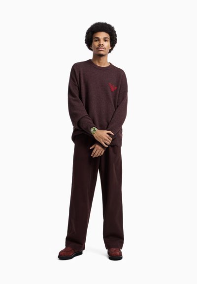 Maglione a maglia bordeaux con un logo sottile, vestibilità comoda. Abbinato a pantaloni larghi scuri e scarpe rosse texturizzate. Design leggero.