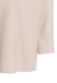 Top in maglia a coste beige con maniche corte, caratterizzato da un fit rilassato e una finitura morbida e texturizzata. Motivo sottile lungo il tessuto.