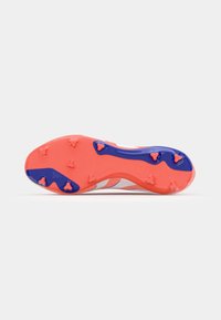 Suela de botas de fútbol rojas y azules con tachuelas moldeadas; presenta "PREDATOR" en relieve, superficie texturizada y acentos de color contrastante.