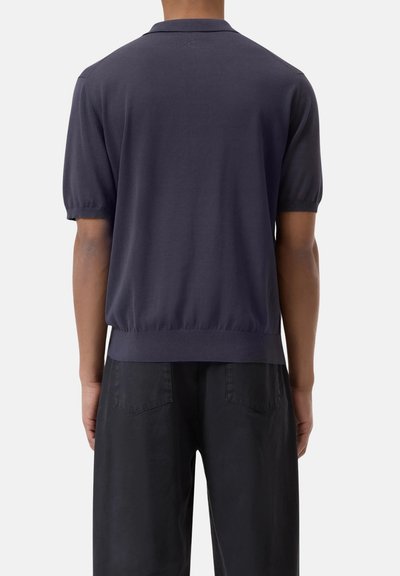Polo shirt lavorato a maglia di un blu navy scuro con colletto piatto, maniche corte e orlo a costine; texture liscia e silhouette aderente.