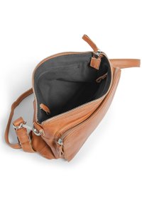Tan läder crossbody-väska med dragkedjestängning, svart tyginredning och silverfärgade metalldetaljer. Har en ytterficka med dragkedja.