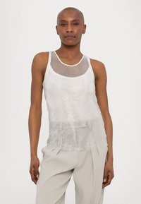 Zilveren gemeshde tanktop met een wijde halslijn en schouderbanden, met een losse pasvorm en een gelaagde, gestructureerde uitstraling. Draagt bij lichte, gekleurde broek.