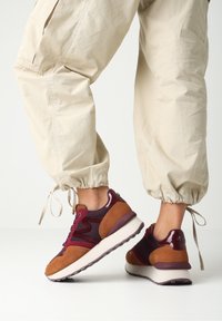 Baskets en suède bordeaux et marron avec des panneaux en maille, une semelle rembourrée et des accents distinctifs sur le talon.