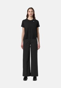 T-shirt nera a maniche corte con vestibilità slim e collo rotondo, abbinata a pantaloni neri a gamba larga e scarpe stringate nere. Design semplice.