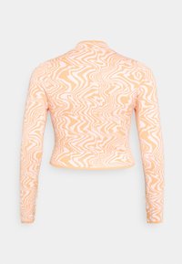 Top cropped de mangas longas em tecido laranja suave, apresentando um padrão branco ondulado. O design é justo ao corpo, com um decote redondo.