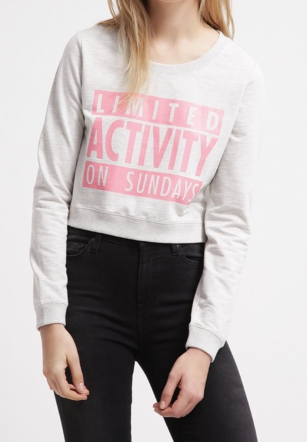 Světle šedý zkrácený sweatshirt s růžovým textem "OMEZENÁ AKTIVITA V NEDĚLI." Obsahuje kulatý výstřih a náplety na rukávech.