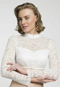 Weißes Spitzen-Crop-Top mit hohem Kragen, langen Ärmeln und gewellten Bündchen. Texturiertes Blumenmuster über das gesamte Kleidungsstück.