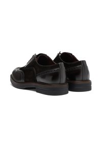 Scarpe in pelle e suede marrone scuro con punta lucida, dettagli brogue e una robusta suola in gomma nera. Stile con chiusura stringata.
