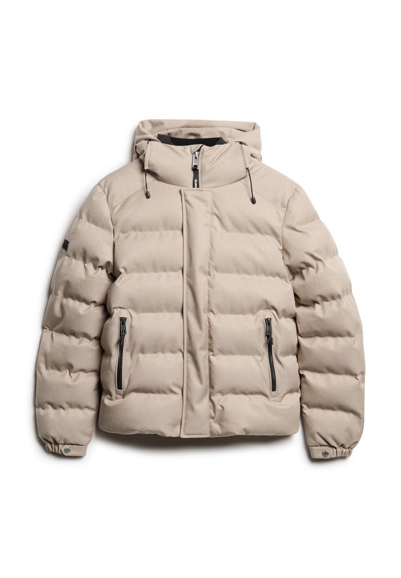 Beige pufferjack met een capuchon, voorzien van een rits aan de voorkant, elastische manchetten en twee ritszakken aan de zijkant. Gestructureerd, gewatteerd oppervlak.