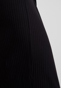 Tissu noir côtelé, design ajusté, rayures verticales, texture douce, mi-long. Convient pour un port décontracté ou ajusté.