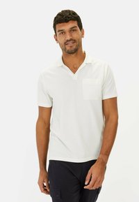 Hvid kortærmet polo shirt med et tekstureret materiale, der har en krave og en lille brystlomme. Simpelt design, afslappet pasform.