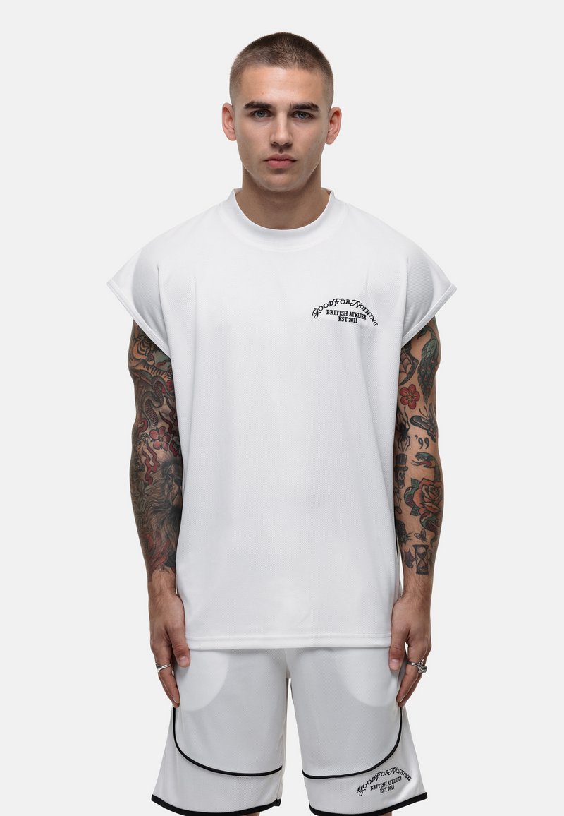 Witte oversized T-shirt met korte mouwen en een ronde halslijn, versierd met een geborduurd logo. Gekozen in combinatie met bijpassende witte shorts met zwarte accenten.