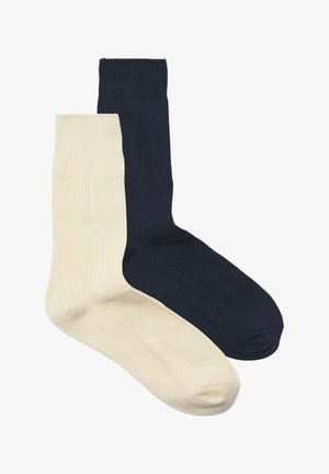 Katoenen sokken in crème en marine, met een geribbeld textuur en een standaard crewlengte. Geen zichtbare branding of patronen.