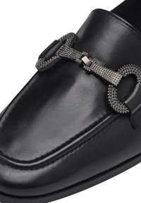 Mocassini in pelle nera con accentuazione di catena argentata testurizzata. Finitura liscia con dettagli di cucitura sottili, punta arrotondata e profilo basso.