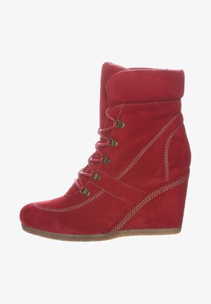 Czerwone zamszowe botki na koturnie z wiązaniem z przodu, kontrastującym białym ściegiem i okrągłym noskiem. Posiadają wyściółkę w okolicy kostki dla wygody.