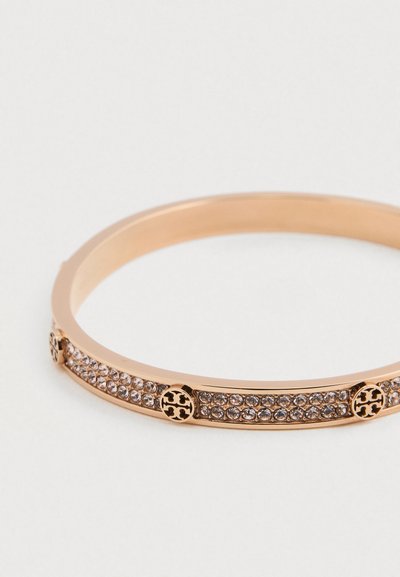 Pulseira circular dourada com filas de cristais transparentes e três acentos decorativos redondos igualmente espaçados sobre um fundo branco.