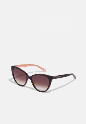 Cat-eye sunglasses with dark tortoiseshell frames and gradient brown lenses. Pink accent on the arms features brand logo in gold.
