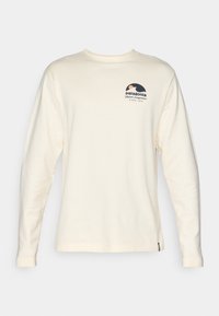 Kermansävyinen pitkähiha paita, valmistettu puuvillasta. Varustettu pyöreällä pääntiellä ja vasemmassa rinnassa sinisen, oranssin ja mustan värisellä grafiikalla varustetulla logolla.