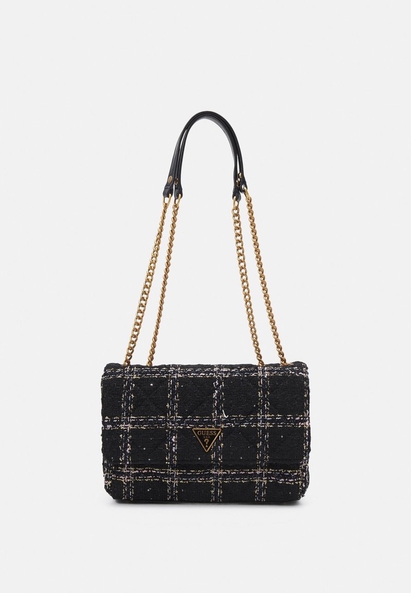 Sac d'épaule en tweed noir avec motif à carreaux blancs, bandoulières chaînes dorées et un logo Guess doré triangulaire sur le rabat avant.