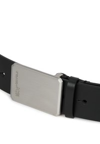 Mustmustri nahkavöö, millel on ristkülikukujuline hõbedane metallist pandla, millel on harjatud viimistlus ja reljeefne kaubamärk. Ükslane tekstuur üle kogu pinna.