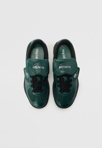 Groene synthetische sneakers met zwarte accenten, voorzien van een klittenbandsluiting, een textuur oppervlak en "Slytherin" branding op de band en inlegzool.