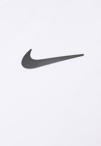 Tela blanca con una superficie texturizada que presenta un logo negro de Nike en el lado izquierdo. El diseño es minimalista y elegante.