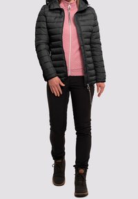 Zwarte gewatteerde jas met een slimfit ontwerp, rits aan de voorkant en capuchon, gedragen over een roze textuur rits-top, gecombineerd met zwarte broeken en stevige veterschoenen.