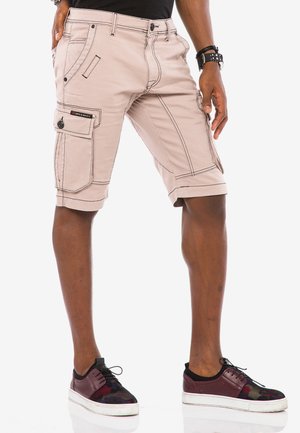 Helle beige Cargo-Shorts mit Steppdetails und Seitentaschen, im lässigen Schnitt mit umgeschlagenen Säumen, kombiniert mit dunklen, gemusterten Sneakern.