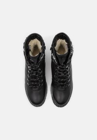 Botas de tobillo de cuero negro con forro de piel, puntera redonda y detalle de cordones en contraste. Cuenta con un cuello acolchado y suela texturizada para mayor agarre.
