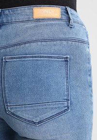 Jeans de mezclilla de color azul claro con una etiqueta "ONLY" en la cinturilla, que presentan bolsillos traseros con costuras en contraste y una textura suave.
