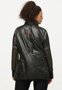 Giacca leggera nera con colletto alto, maniche in rete, dettagli riflettenti e la scritta "HYPRAR" stampata in rosso sul retro.