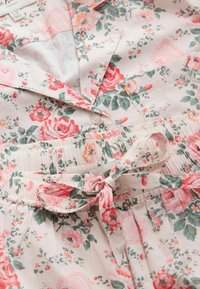 Mäkký bavlnený pyžamový set s ružovým a zeleným kvetinovým vzorom, vrchný diel na zapínanie na gombíky a nohavice s elastickým pásom previazané pásikom z rovnakého materiálu.