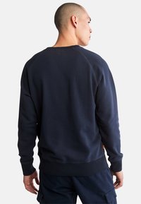 Felpa blu navy con polsini e orlo a costine. Presenta un classico collo a giro e un tessuto morbido; include un piccolo etichetta arancione sul lato.