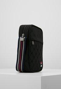 Borsa in tessuto nero con motivo embossato, chiusura con zip e manico a strisce con dettagli rossi, bianchi e blu. Logo visibile.