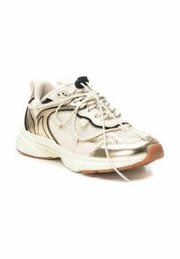 Zapatilla con parte superior de malla y sintético. Presenta acentos dorados, suela blanca y cordones planos. El diseño incluye paneles texturizados y un logo minimalista.