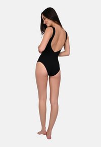 Black one-piece swimsuit with a low back, wide shoulder straps, and a snug fit. Smooth texture and minimal coverage at the legs.