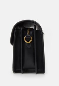 Borsa in pelle nera con forma strutturata, dettagli in cerniera dorata e un prominente hardware ad anello. L'interno presenta sezioni divise.