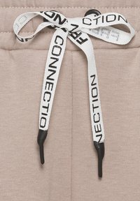 Beige Sweatpants aus strukturiertem Stoff, mit einem elastischen Bund und einem kontrastierenden weißen Kordelzug mit schwarzen Textakzenten.