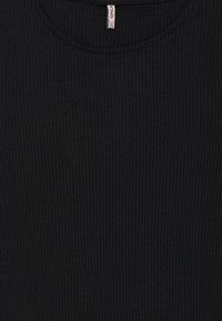 Μαύρο ribbed πλεκτό ύφασμα με στρογγυλή λαιμόκοψη και μια μικρή λευκή ετικέτα ρούχων στο κέντρο στην κορυφή.