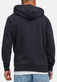 Sweat-shirt noir avec une capuche spacieuse, des poignets et un ourlet côtelés. Matière en mélange de coton, texture lisse, sans motifs ni accents visibles.