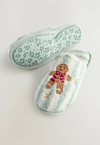 Papuci pufoși de culoare verde mentă, cu dungi orizontale, având un design de om de turtă dulce pufos și un model texturat în formă de stele pe talpă.
