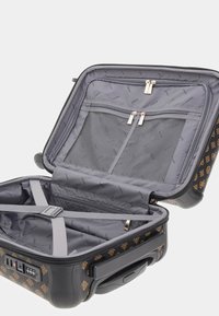 Hard-shell suitcase with brown patterned exterior, gray interior, zippered compartments, adjustable straps, and combination lock.