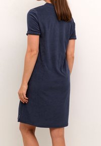 Robe en éponge douce bleu marine avec manches courtes retroussées et coupe droite. Dispose d'une fente latérale pour faciliter les mouvements.