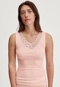 Roze geribbelde tanktop met een diepe V-hals versierd met witte kant. De stof is zacht en accentueert een aansluitende silhouette.