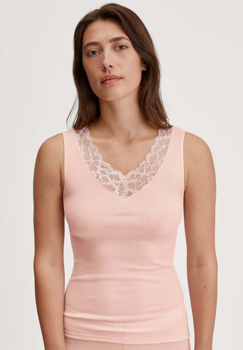 Roze geribbelde tanktop met een diepe V-hals versierd met witte kant. De stof is zacht en accentueert een aansluitende silhouette.